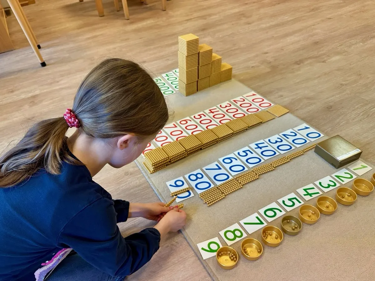Vorschulkind arbeitet mit dem goldenen Perlenmaterial